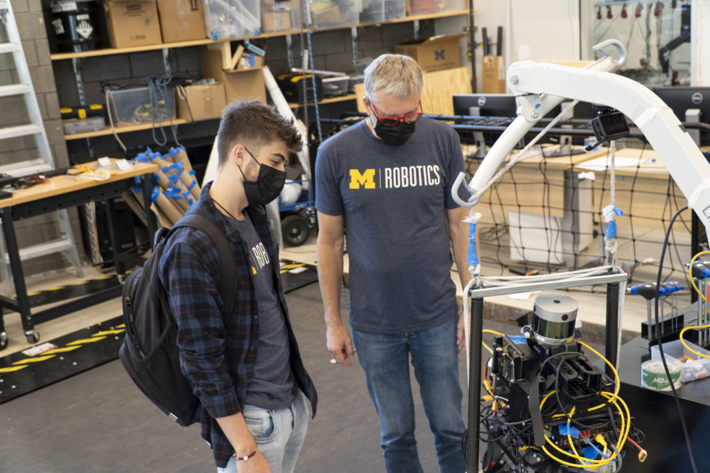 Professor Jessy Grizzle shows Victor Popa-Simil a Cassie robot with a lidar sensor on top.